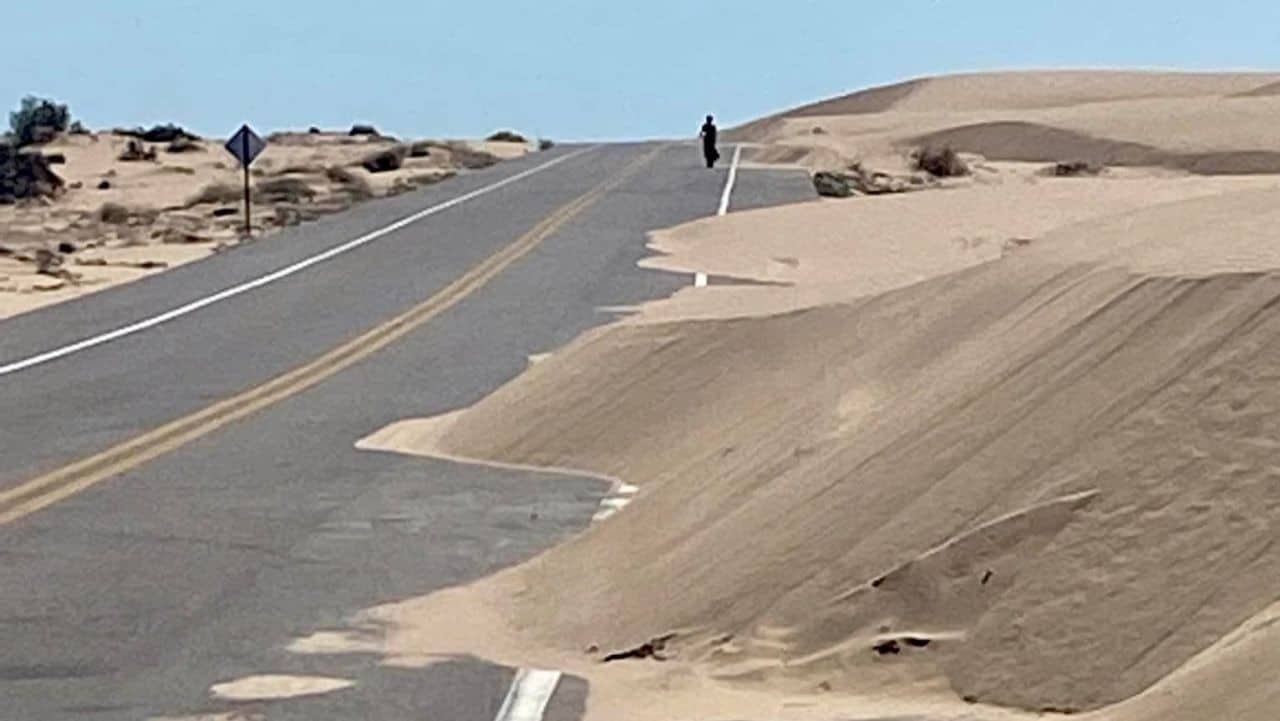 Sand drifts block a lane on the road in front of a cyclist in Northern Mexico.