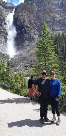 A pair of happy hikers enjoy Takakkaw Falls after a multi-day backcountry camping trip in Yoho National Park BC Canada