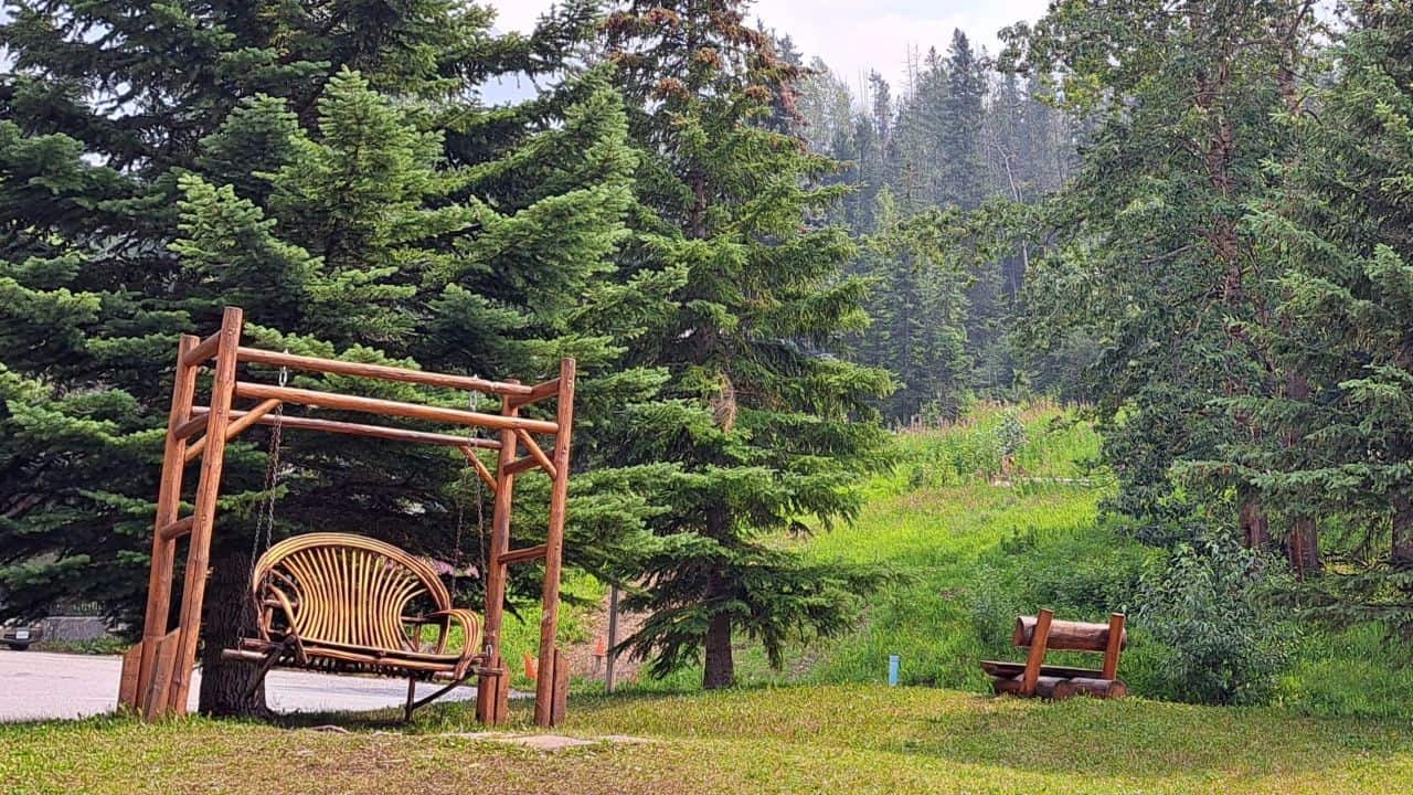 A picturesque garden park with a rustic swing and garden bench for visitors to enjoy while exploring Field BC Canada
