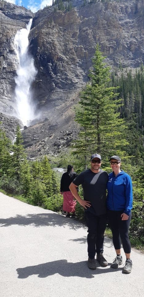 A sightseeing couple stops to admired one of Canada's tallest waterfalls, Takakkaw Falls in Yoho National Park BC