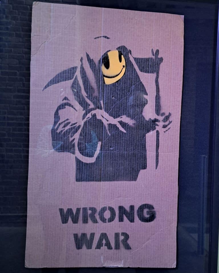 Banksy is calling out the portrayal of war in a positive light when it causes so much death on this antiwar cardboard protest sign