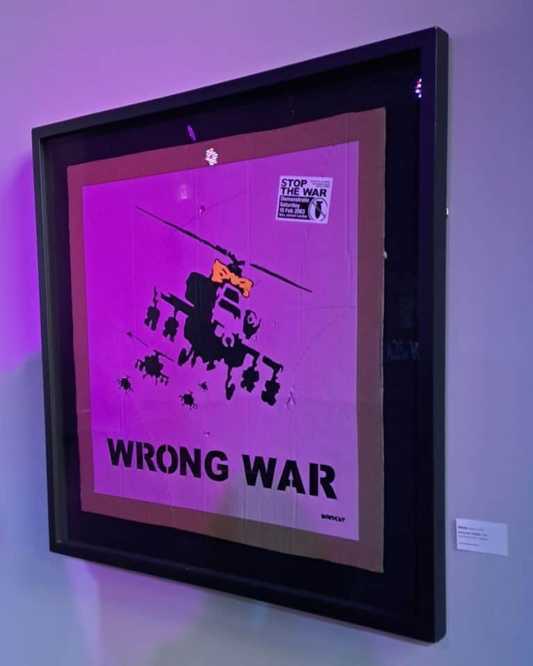 An Apache helicopter wearing a bow is off to war on the antiwar protest sign at the Banksy Art Event in Edmonton.