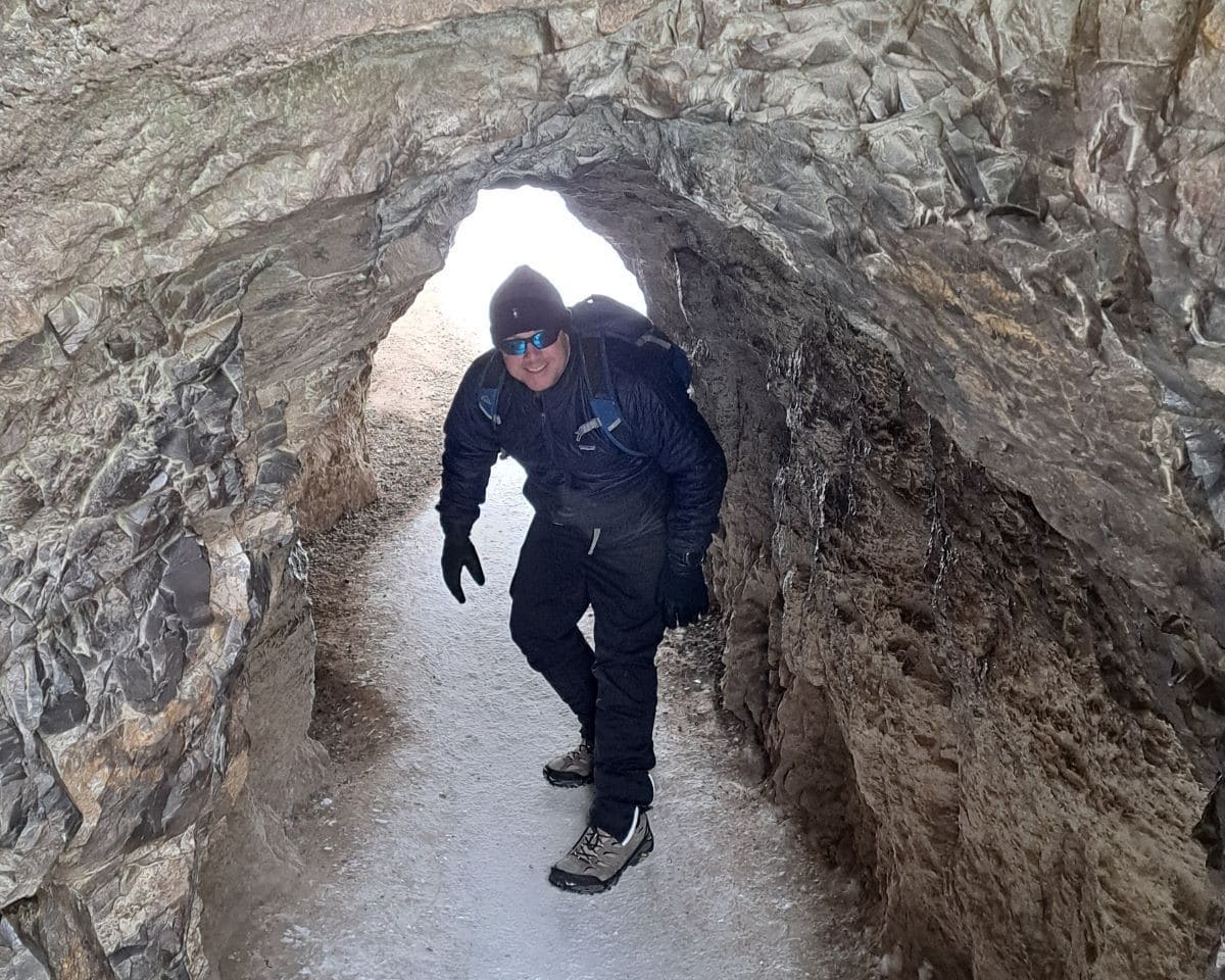 An advenutre seeker hiking the Johnston Canyon Trail in the winter ducks as he passes through a cave to get a close up view of the Lower Falls.