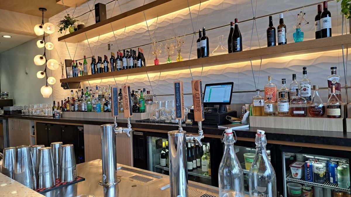 A well stocked bar with natural and organic feeling decor welcomes diners to Gather Craft Kitchen and Bar at The Leaf in Winnipeg.