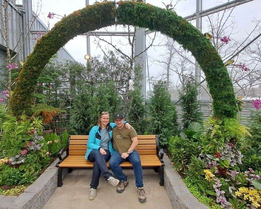 A couple sits on a bench beneath a living arch in the Babs Asper Display House at The Leaf in Assiniboine Park.