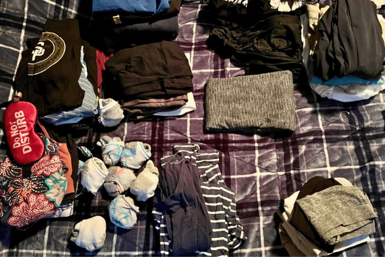What to Pack for a Cross Canada Road Trip - Stacks of clothing, sorted and folded, ready to be packed for a cross-Canada road trip.