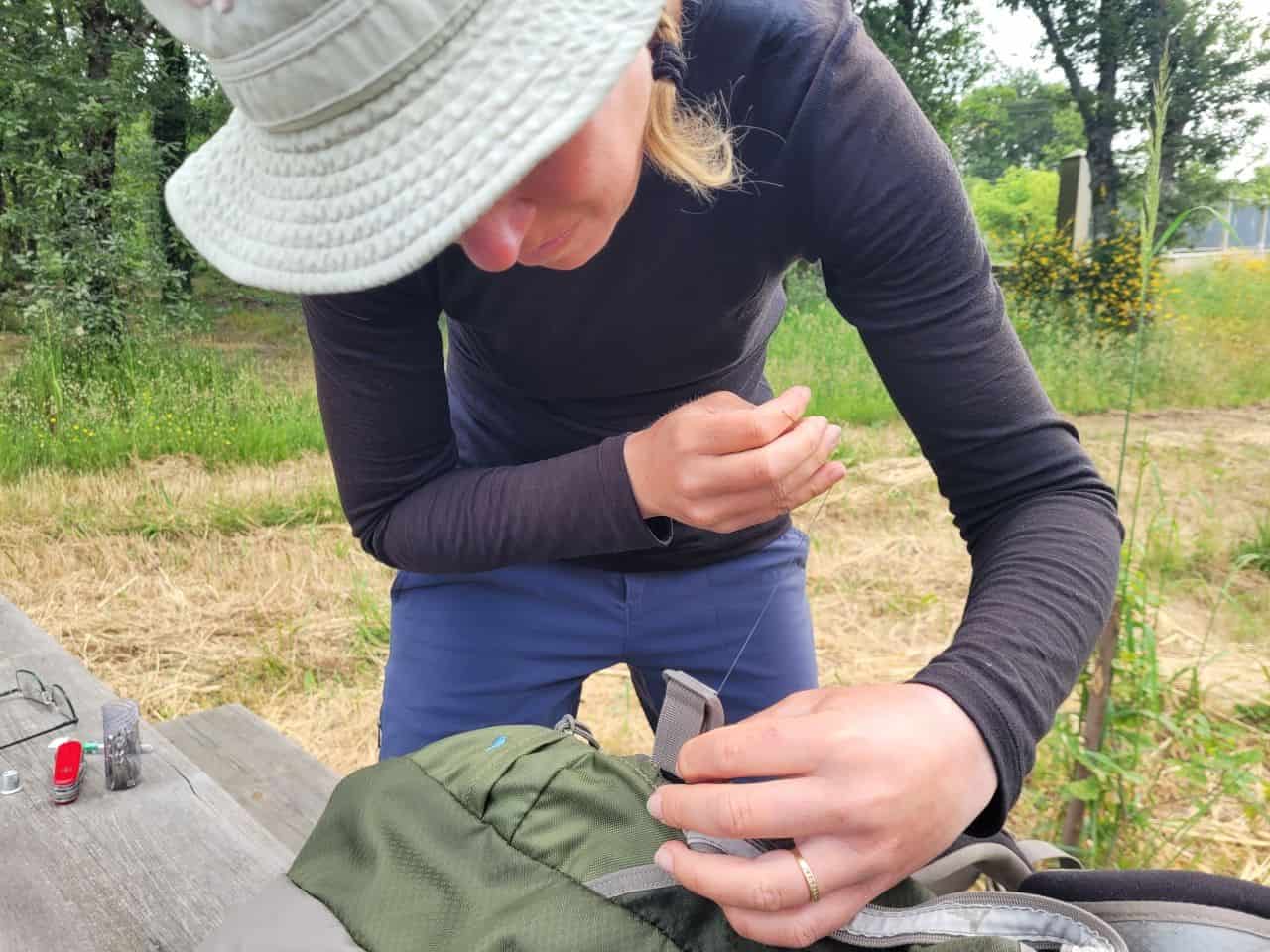 Sonya stitches Sean's backpack back together with our trusty sewing and repair kit, a must-have for any long-distance trek. Preparedness and adaptability make all the difference on the trail.