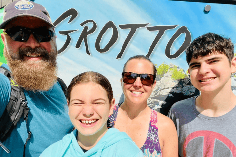 Four people smile in front of a sign that says 