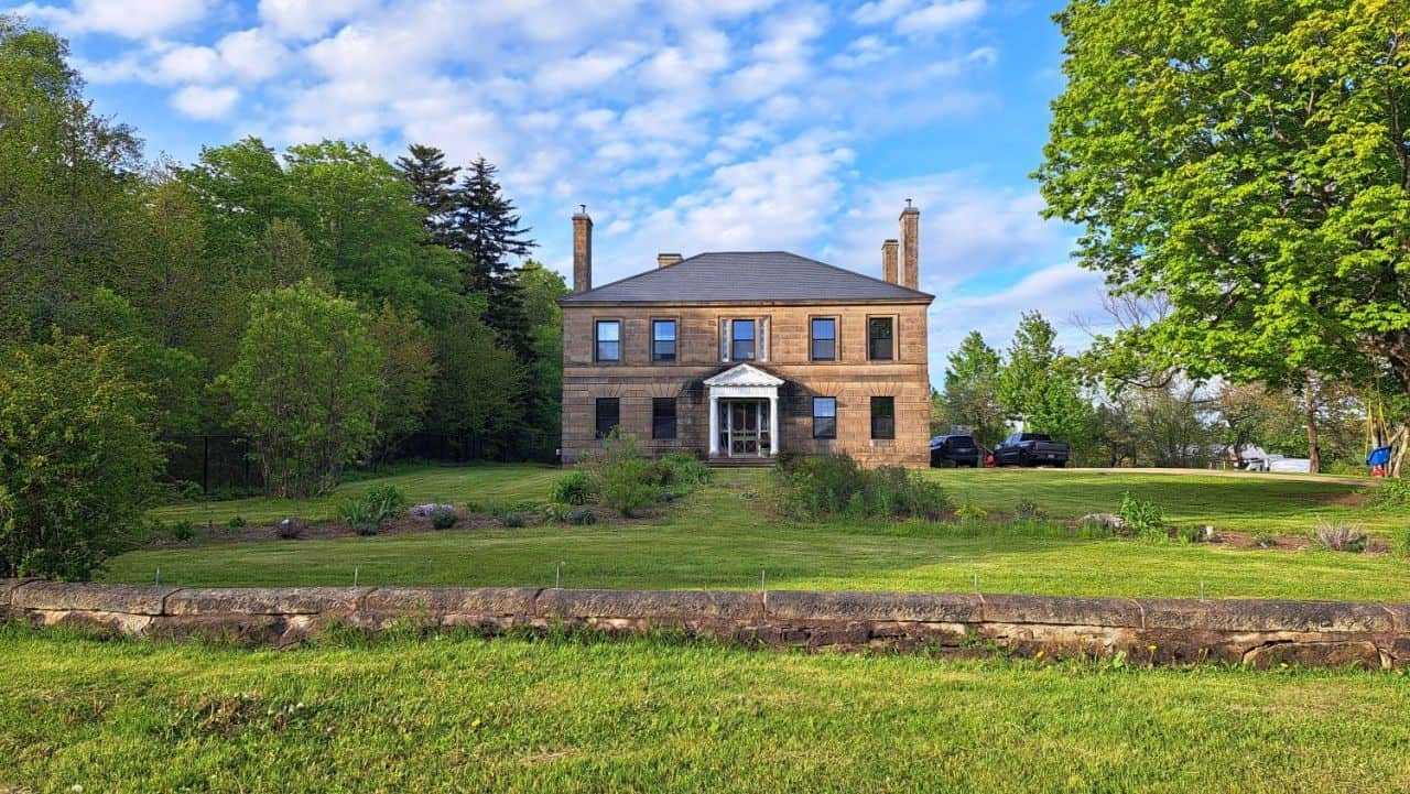 Explore Dorchester, New Brunswick: A Slow Adventure filled with historic homes and heritage. The photo shows a two story stone house that belonged to Edward Barron Chandler one of the Father's of Confederation in Canada.
