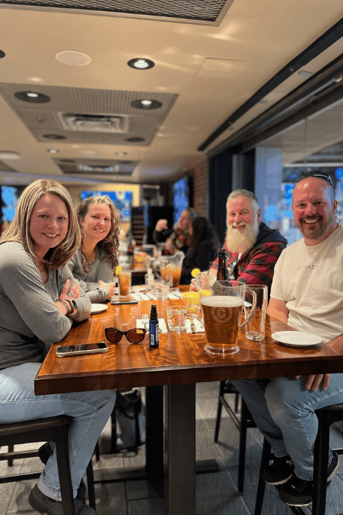 Dinner at La Cage, in the Bell Centre, Montreal, Quebec. A group of adults smiling in the restaurant before the Mumford and Sons concert.