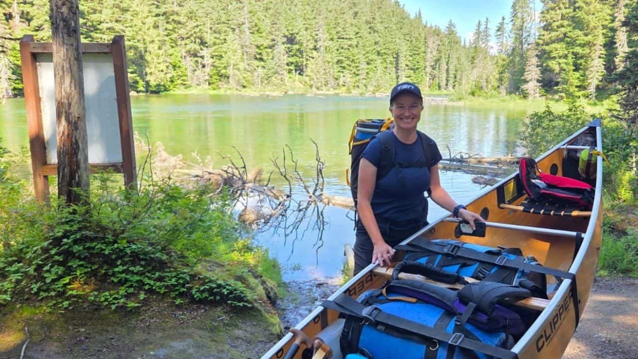 A female paddler is all smiles after braving The Chute and the Roller Coaster on the Bowron Lakes Canoe Circuit while she prepares the canoe for the next portage.