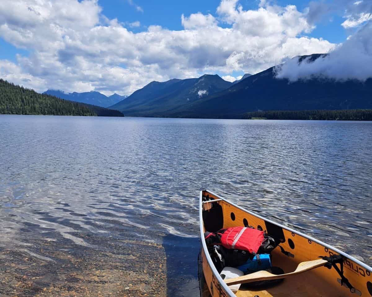 A canoe being loaded after a portage with a view of a beautiful day on Indianpoint Lake on the Bowron Lake Canoe Circuit.