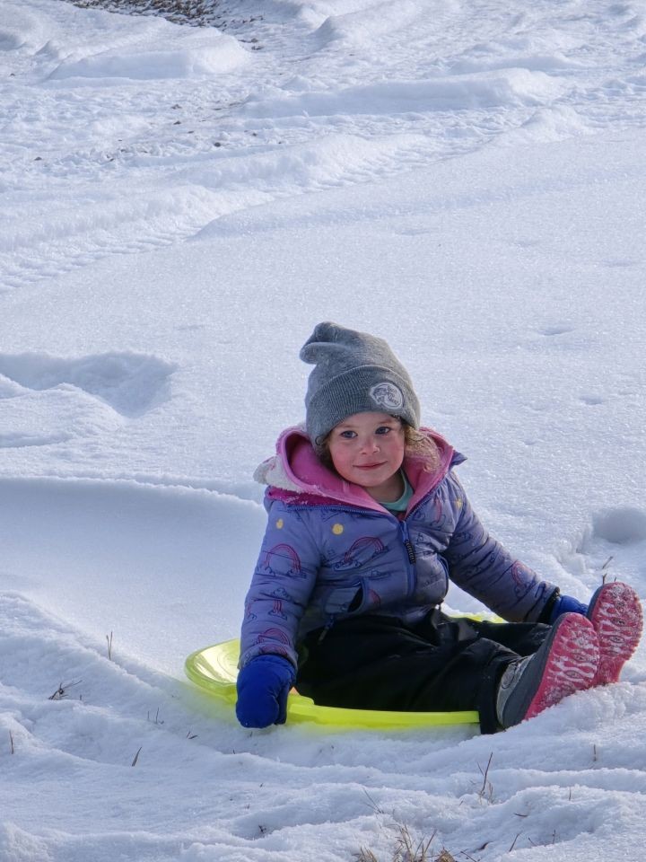 A child tobogganing in the snow at Bearberry Cabins in Sundre, Alberta, Canada. during winter.