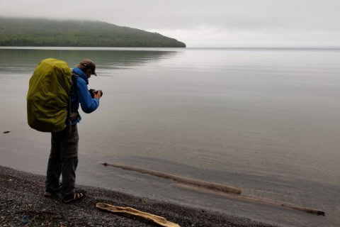 Pausing on a misty beach along the Kabeyun Trail in Sleeping Giant Provincial Park near Thunder Bay, where Lake Superior shoreline hiking meets remote wilderness and changing weather conditions.