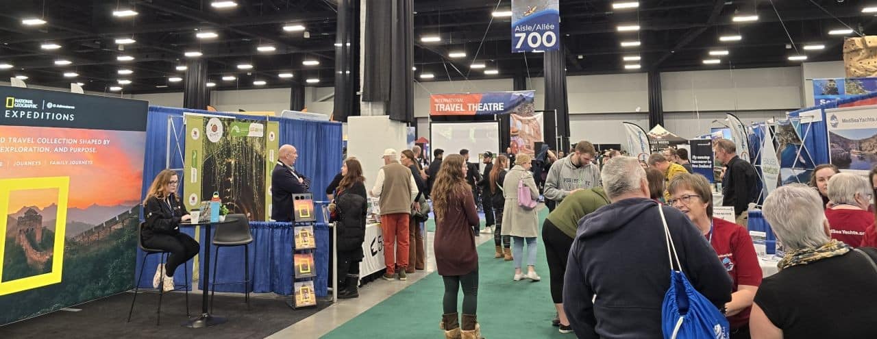 Crowds walking through the Calgary Outdoor Adventure & Travel Show at the BMO Centre in Calgary, Alberta, with travel booths, outdoor gear displays, and vendors from Canada and international destinations.