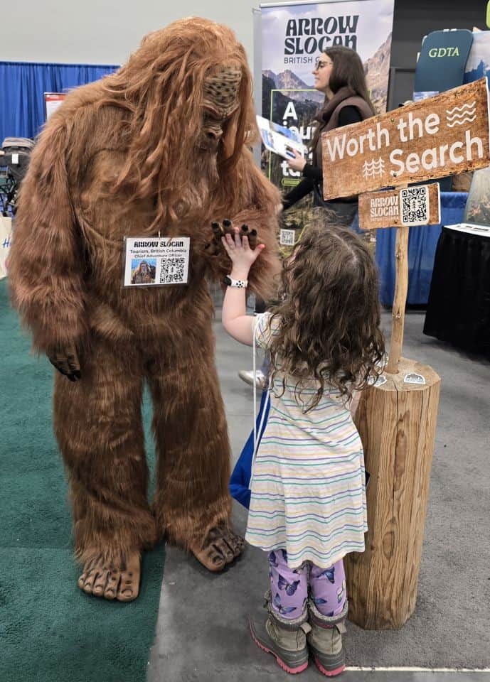 Child giving a high five to the Arrow Slocan Sasquatch mascot at the Calgary Outdoor Adventure & Travel Show in Calgary, Alberta.