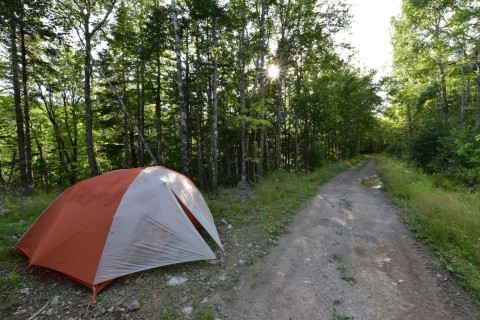 A tent set up beside the Celtic Shores Coastal Trail highlights bikepacking and camping opportunities along scenic Trans Canada Trail routes, where cyclists can stay close to nature and coastal landscapes.