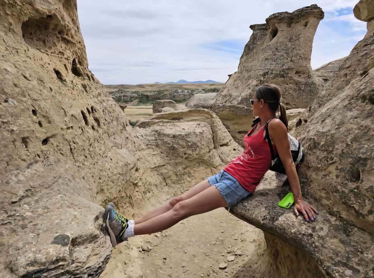 Woman overlooking sandstone formations while hiking at Writing-on-Stone Provincial Park in Alberta Canada