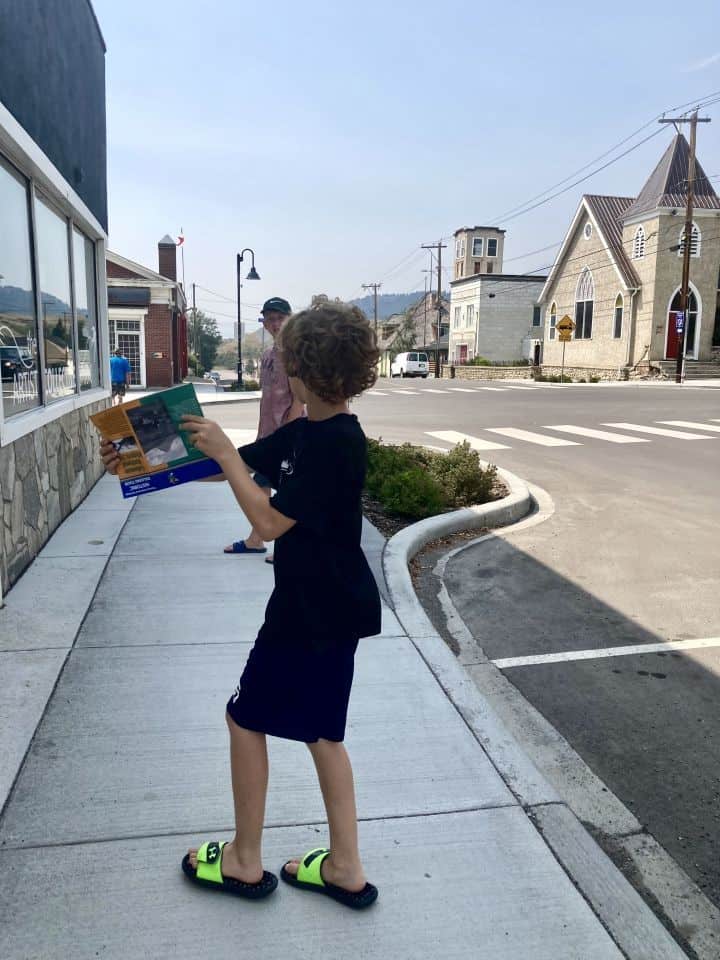 Young boy holding a walking tour pamphlet on street in Coleman Alberta Canada.