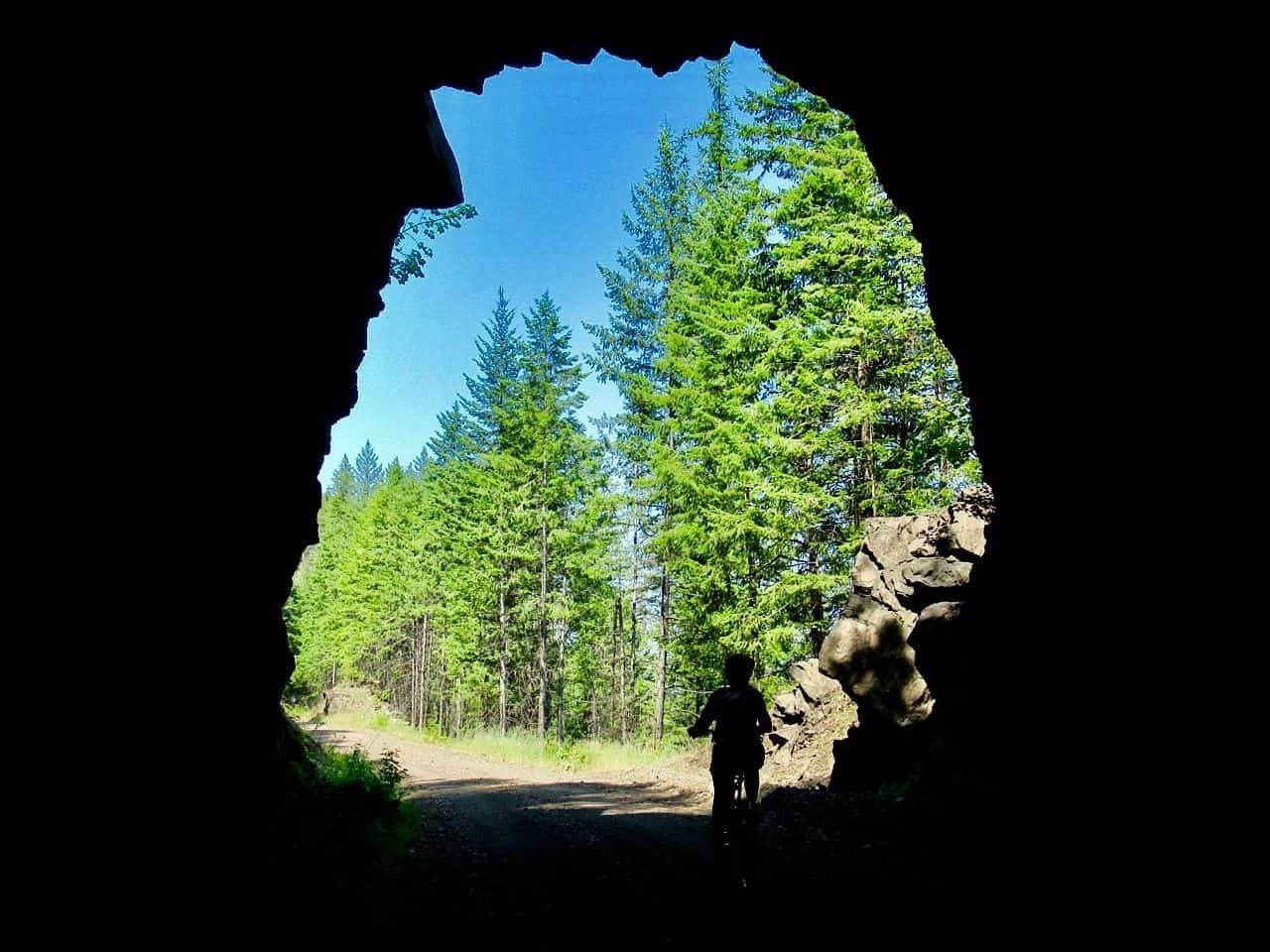 Shadowy image of person on bike coming out of dark tunnel in Castlegar BC Canada.