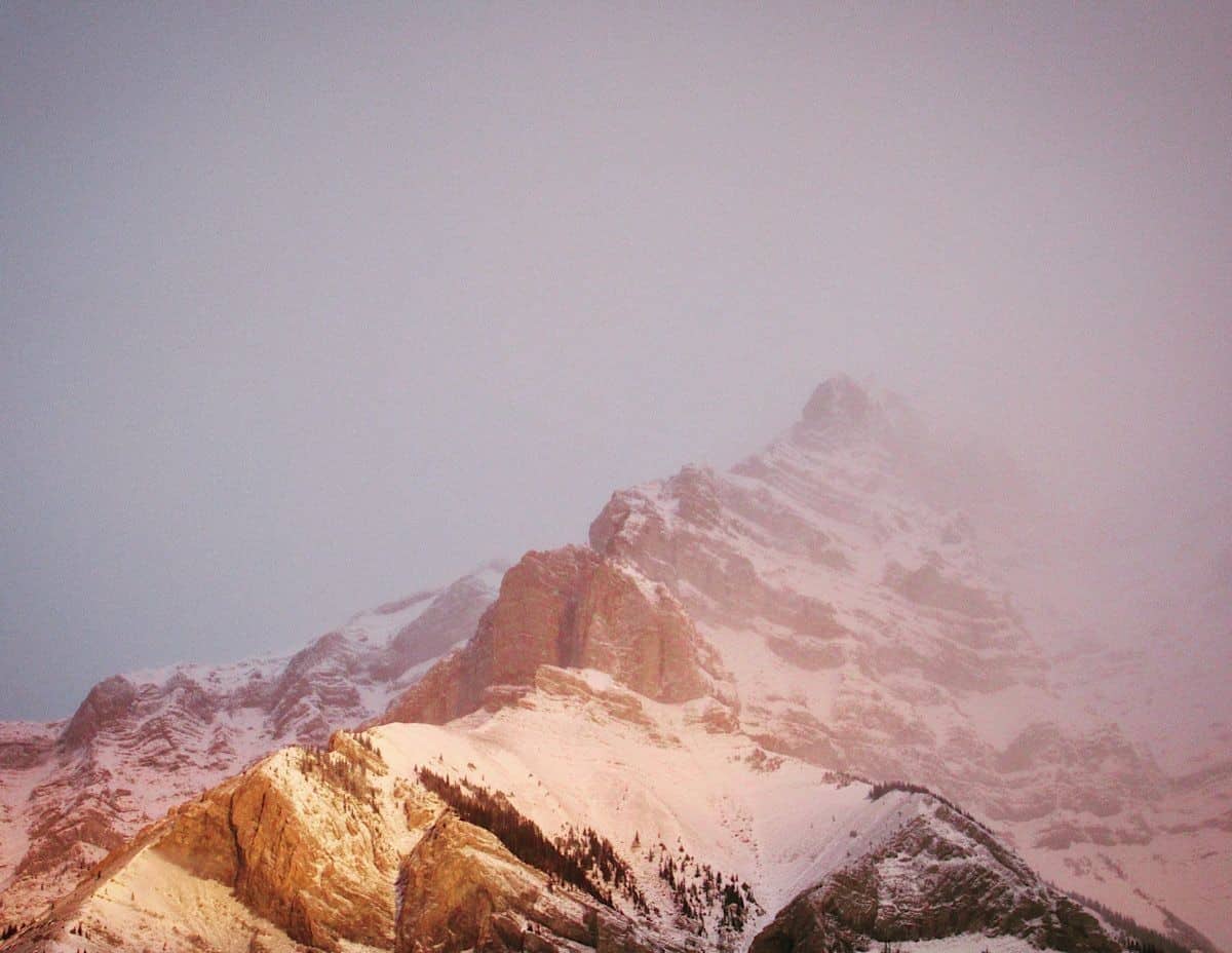 Morning light glowing on a misty and snow-covered rugged mountain peak in Banff Alberta Canada