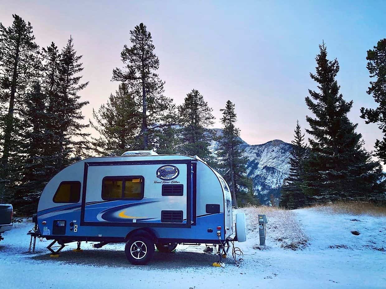 Blue and white trailer in snow-covered campsite in Banff National Park