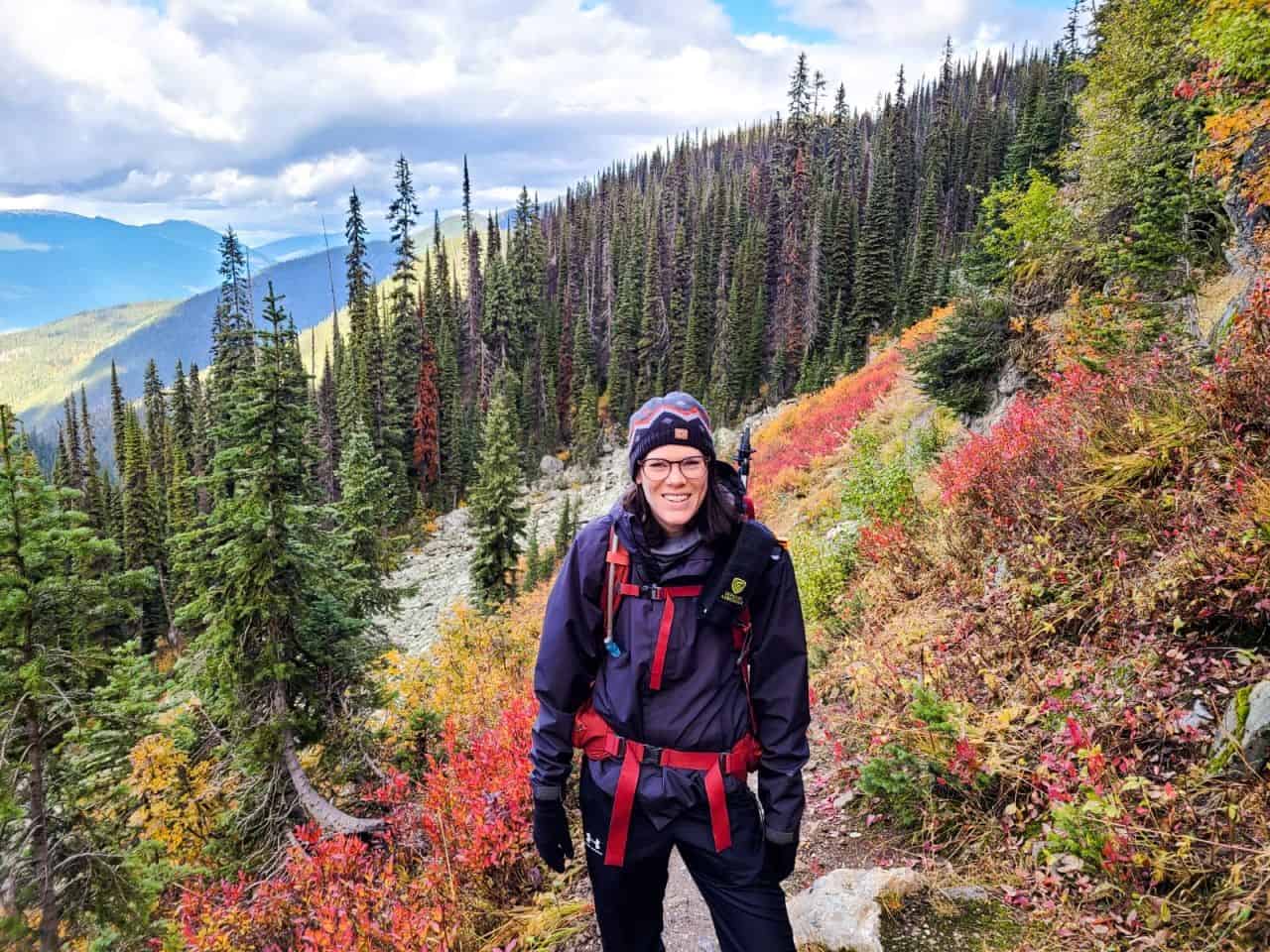 Girl hiking in the fall with trees behind