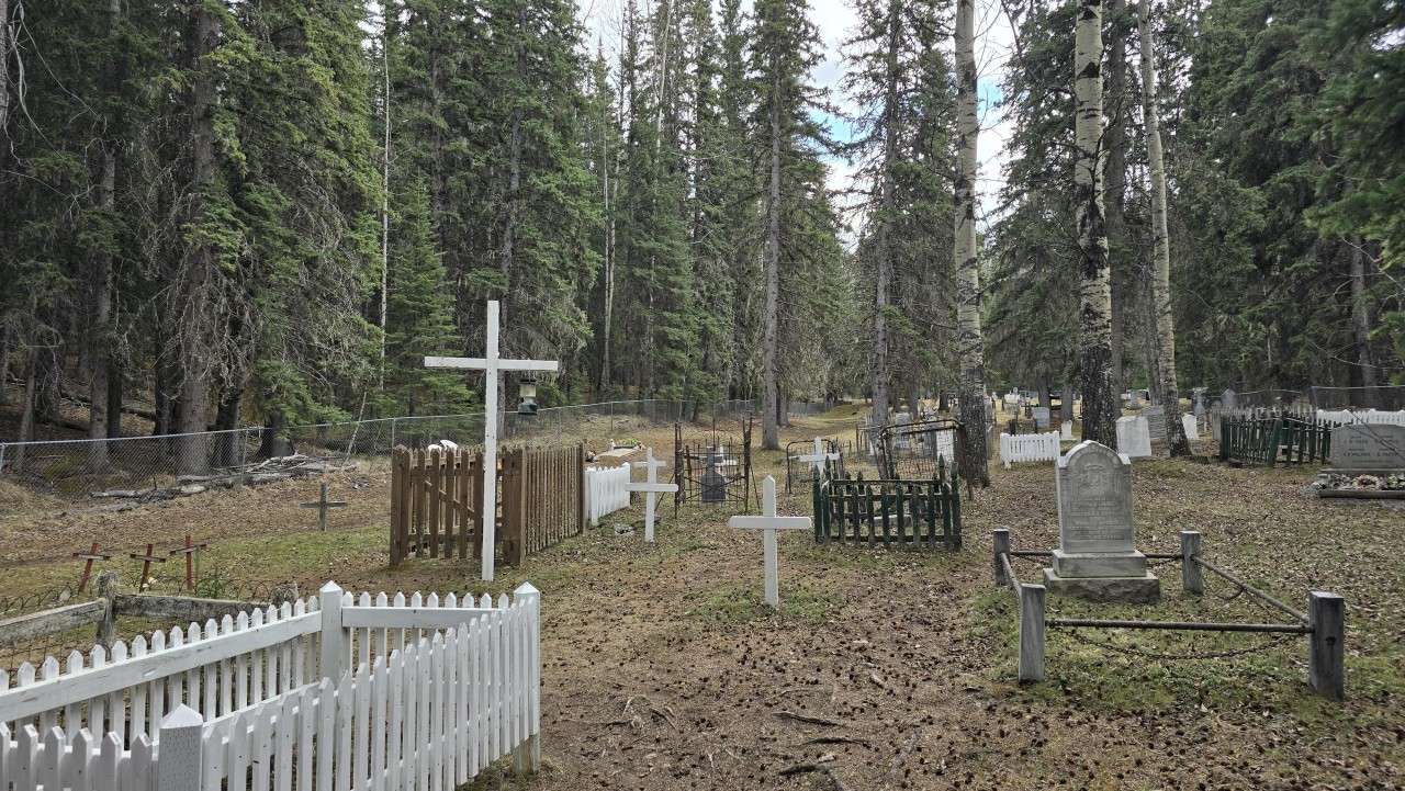 Crosses and Fenced Plots in Nordegg Cemetery - A wide view of the older Nordegg cemetery reveals white crosses, family fences, metal railings, and layered burial styles. Not your typical copy and paste grid system cemetery found nowadays 