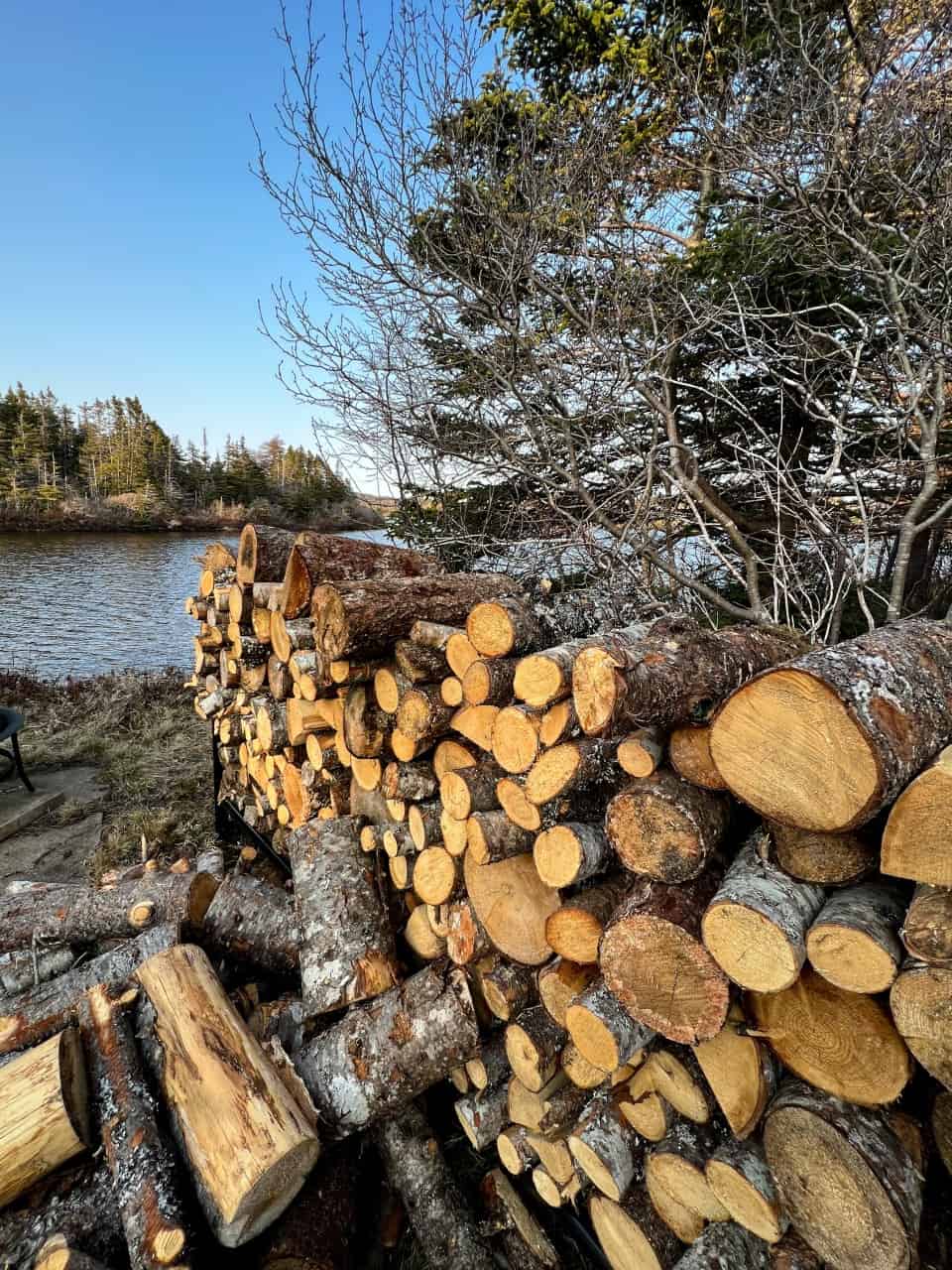Wood pile by the Pond at the Cottage Fire Pit in Newfoundland Canada - Relaxing at the outdoor fire pit was my favourite place to be at The Murphy Cottage in Newfoundland Canada. There was plenty of fire wood available and I loved watching both sunrise and sunset over the lake. 